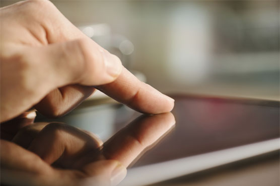 A hand is touching the screen of a tablet device, exploring Three Photoshop Tricks to Enhance and Extend Your Images.