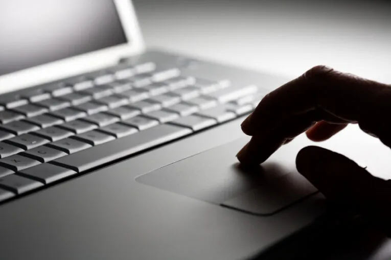 A person's hand using the touchpad of a laptop, possibly drafting a guide on "How to Write a Law Firm Press Release".