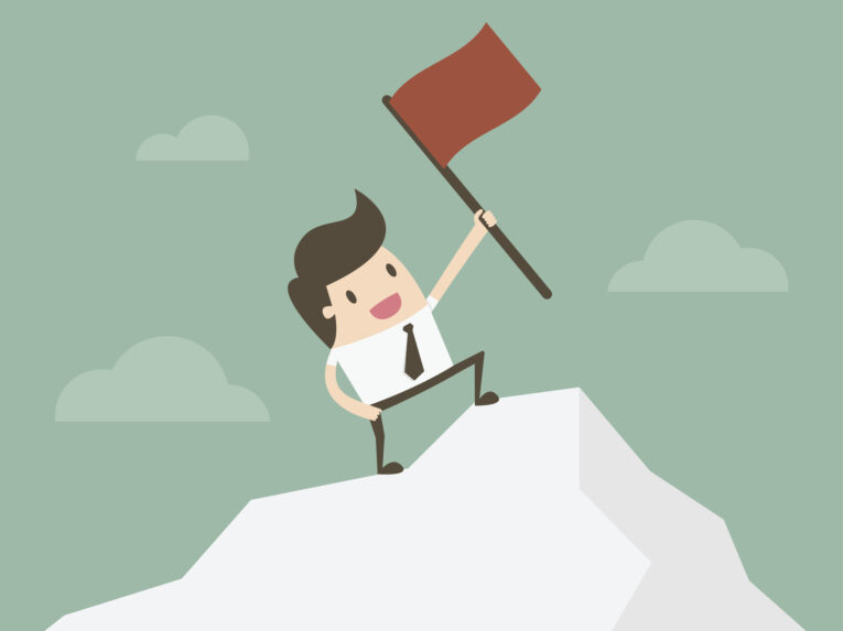 A cartoon man in a white shirt and tie stands on a mountain peak holding a red flag.