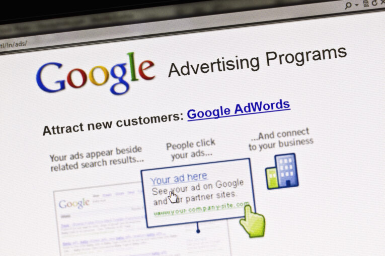A Google Advertising Programs webpage highlighting Google AdWords, showing examples of how ads appear beside search results, with linked text and a cursor pointing to an ad.