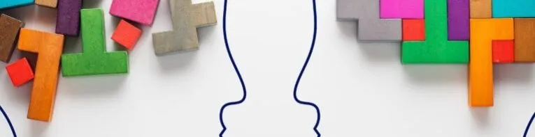 Two outlined human profiles face each other, with colorful interlocking puzzle pieces emerging from the top of each head, symbolizing the convergence of ideas inspired by the "Seven Common Cures for Writer’s Block.