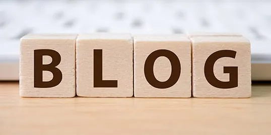 Wooden blocks spelling "BLOG" are arranged in front of a keyboard.