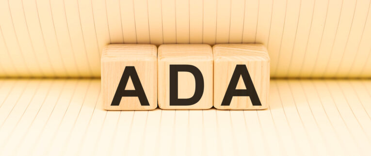 Wooden blocks with the letters "ADA" on a lined background.