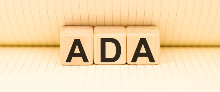 Wooden blocks with the letters "ADA" on a lined background.