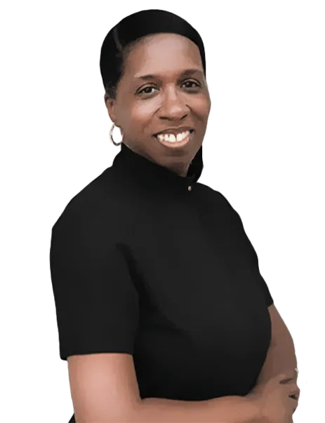 A person with short hair and hoop earrings, wearing a black shirt, is standing with arms crossed and smiling. The background is white.