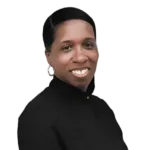 A person with short hair and earrings is smiling, wearing a high-neck black top, against a white background.