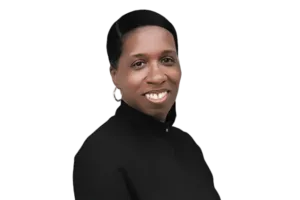 A person with short hair and earrings is smiling, wearing a high-neck black top, against a white background.