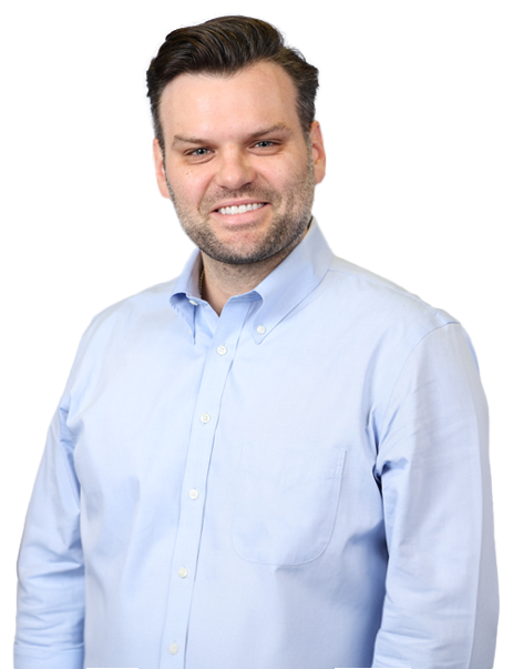 A man with short hair and a beard, wearing a light blue button-down shirt, smiles at the camera.