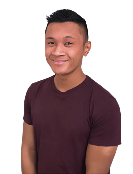 Young man in a maroon t-shirt smiling, standing against a white background.
