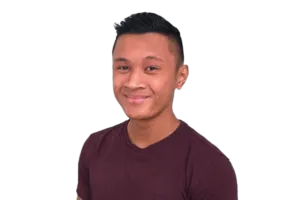Man with short black hair wearing a maroon shirt smiles against a black background.