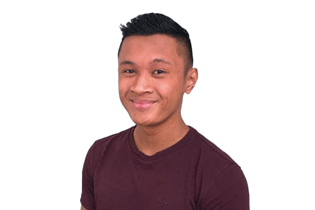 Man with short black hair wearing a maroon shirt smiles against a black background.