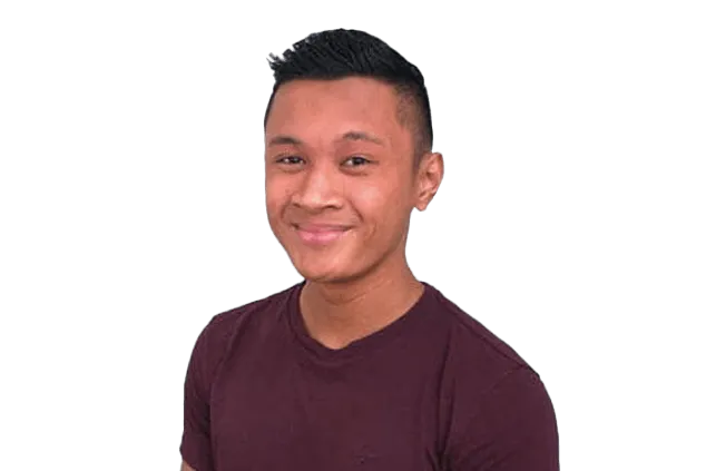 Man with short black hair wearing a maroon shirt smiles against a black background.