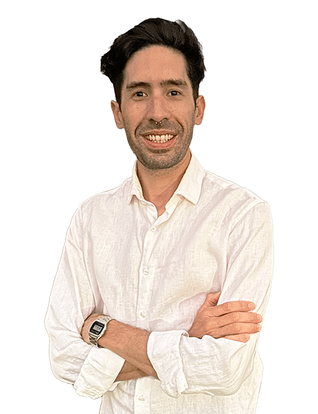 A man with short dark hair and a beard is smiling and wearing a white button-up shirt. His arms are crossed, and he is wearing a watch on his left wrist. The background is plain.