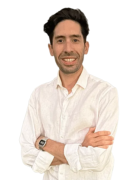 A man with short dark hair and a beard is smiling and wearing a white button-up shirt. His arms are crossed, and he is wearing a watch on his left wrist. The background is plain.