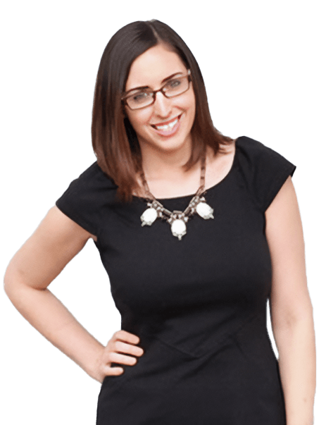 A woman with brown, shoulder-length hair and glasses is smiling. She is wearing a black dress and a necklace with white beads. She has one hand on her hip.