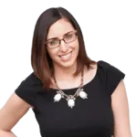 Woman wearing glasses and a black shirt, smiling at the camera.