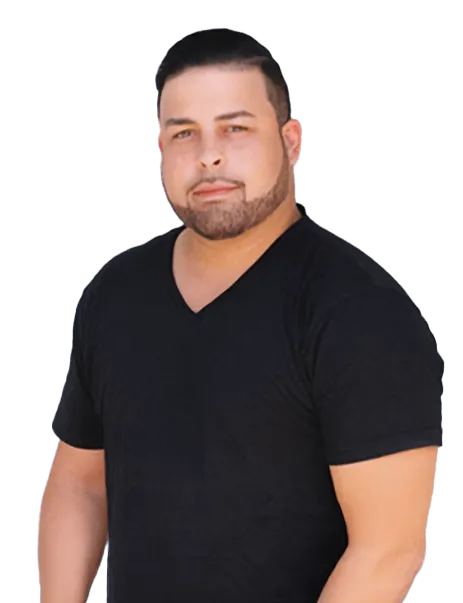 A man with short dark hair and a trimmed beard is wearing a black V-neck T-shirt. He is standing against a white background.