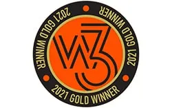A round award badge with a black border and gold text reads "2021 Gold Winner" around the orange center. The center features the stylized letters "W3.
