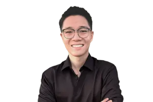 A person wearing glasses and a black shirt smiles with crossed arms in front of a plain, white background.