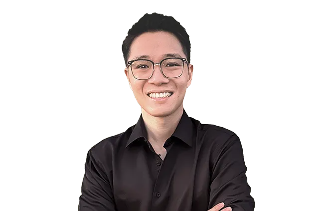 A person wearing glasses and a black shirt smiles with crossed arms in front of a plain, white background.