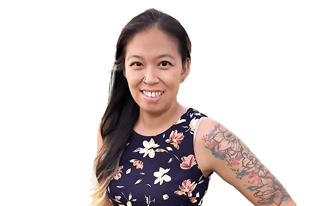 Woman with long dark hair and floral dress smiling, displaying a colorful sleeve tattoo on her left arm. Background is plain white.