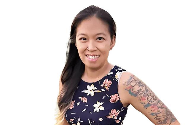 Woman with long dark hair and floral dress smiling, displaying a colorful sleeve tattoo on her left arm. Background is plain white.