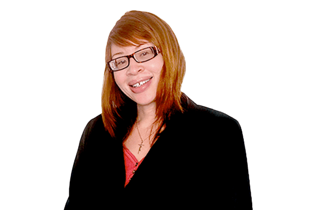 A smiling person with reddish-brown hair and glasses wearing a black blazer over a red shirt.