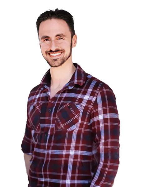 A man with a beard and mustache smiles while wearing a red plaid shirt.