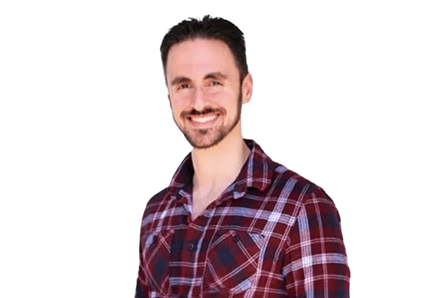 A man with dark hair and a beard smiles at the camera. He is wearing a red plaid shirt.