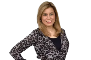 A woman with shoulder-length blonde hair is smiling. She is wearing a leopard-print top over a black shirt.