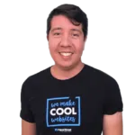 A man smiles while wearing a black t-shirt that reads "we make COOL websites" and "PaperStreet" at the bottom.