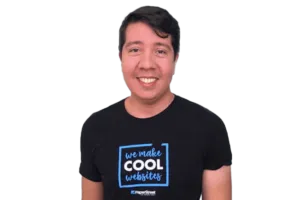 A man smiles while wearing a black t-shirt that reads "we make COOL websites" and "PaperStreet" at the bottom.