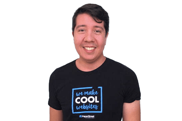 A man smiles while wearing a black t-shirt that reads "we make COOL websites" and "PaperStreet" at the bottom.