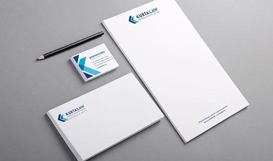 Stationery set including letterhead, business cards, and an envelope, all branded with "Kurt Law" logo and accompanied by a pencil, arranged on a flat grey surface.