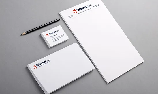 A set of branded stationery including letterhead, business cards, and envelopes with the "Skelton Law" logo and design, placed on a gray surface alongside a pencil.