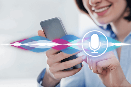 A person holds a smartphone, interacting with a voice assistant, indicated by a colorful sound wave and a microphone icon overlay.