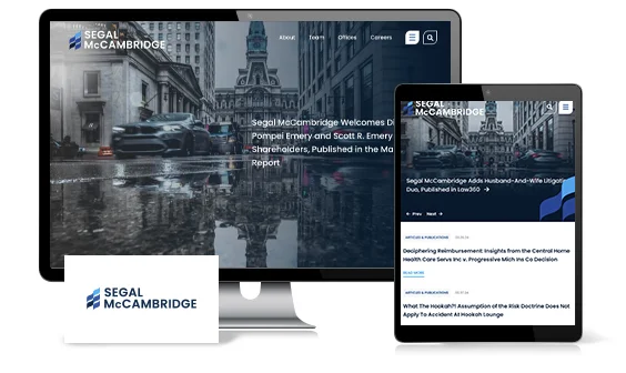 Monitor and tablet display the Segal McCambridge website with a cityscape background. A business card with the Segal McCambridge logo is in the foreground.