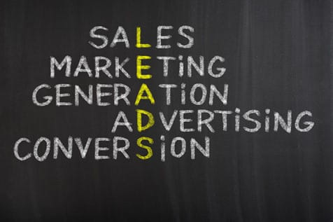 A blackboard with the words "Sales," "Marketing," "Generation," "Advertising," and "Conversion" written vertically, with the letters spelling "LEADS" highlighted in yellow.