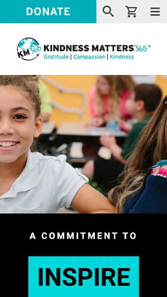 Children sitting at a table in a classroom. The text on the image reads: "Kindness Matters 365 - Gratitude, Compassion, Kindness. A Commitment to Inspire.