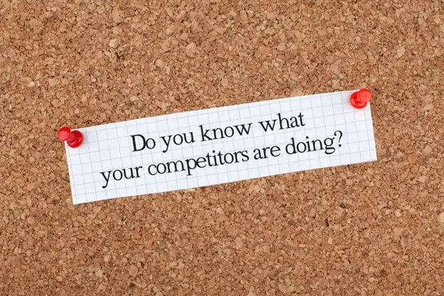 A paper note pinned to a corkboard asks, "Do you know what your competitors are doing?".