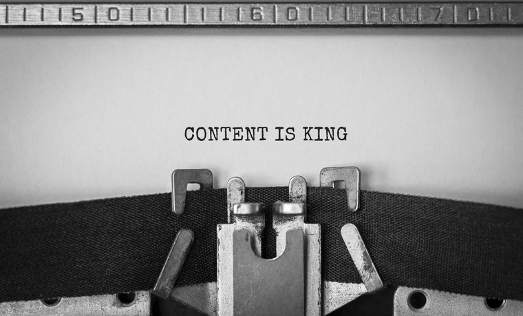 Close-up of typewriter typing the phrase "CONTENT IS KING" on a white sheet of paper.