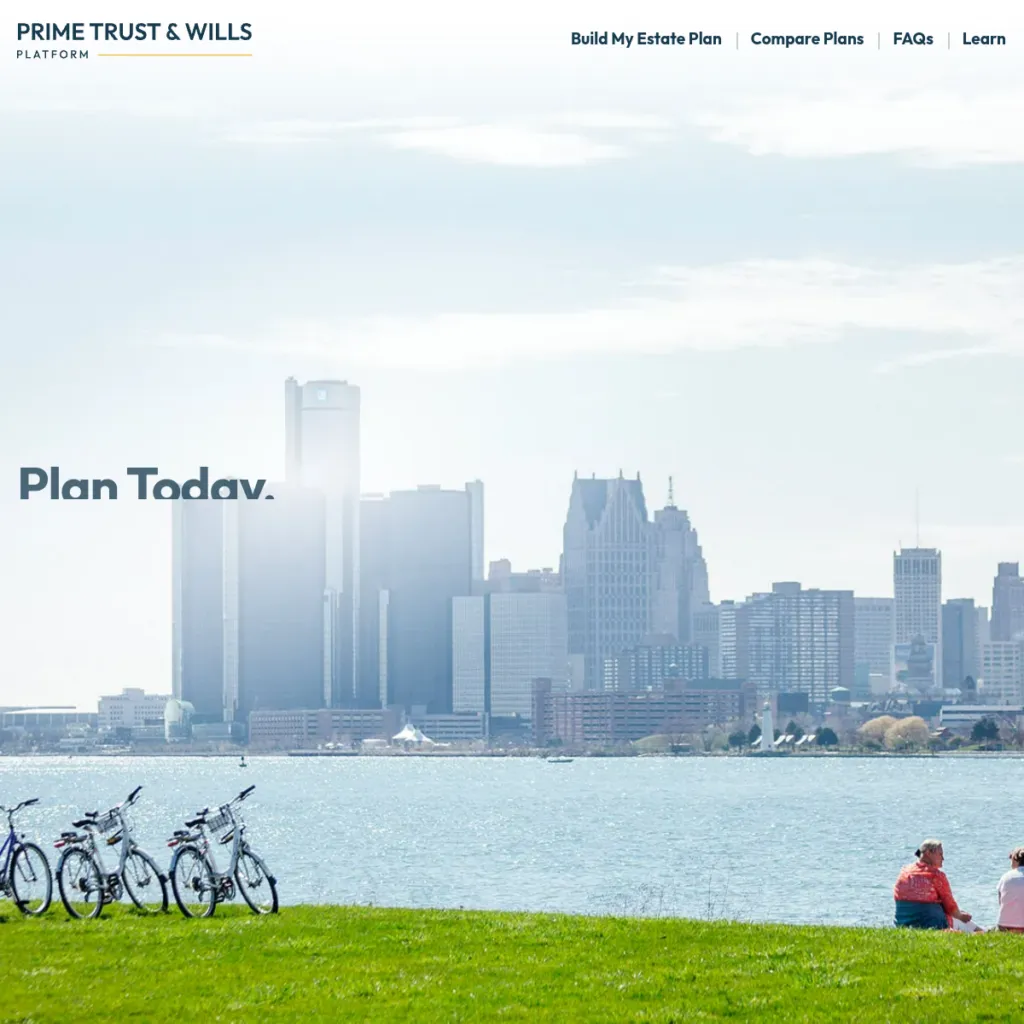 Bicycles on grass by a river with a city skyline in the background under a cloudy sky.