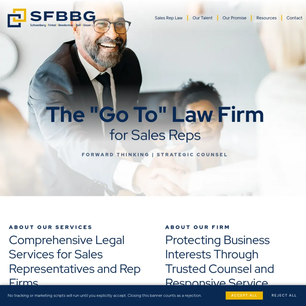 Smiling business people in suits sit at a table, shaking hands in a professional office setting.